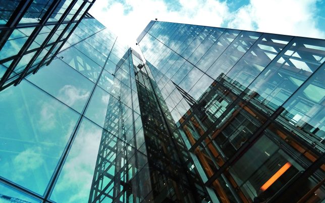 A striking view of a modern glass skyscraper reflecting the sky and clouds.